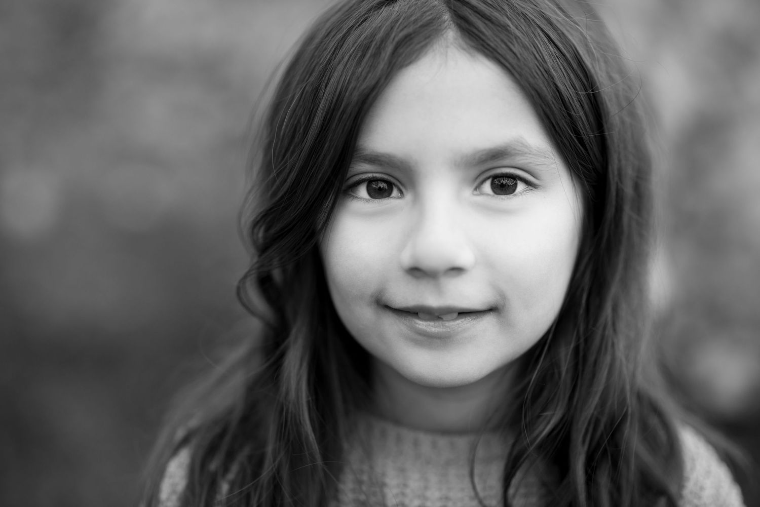 Black and white portrait of a young girl with long dark hair and a gentle smile.