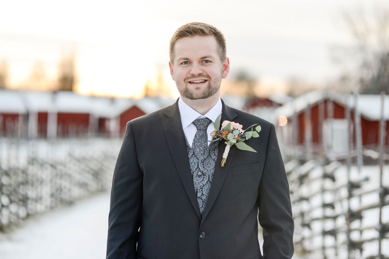 A winter wedding portrait with groomsmen in black suits against a snowy landscape.