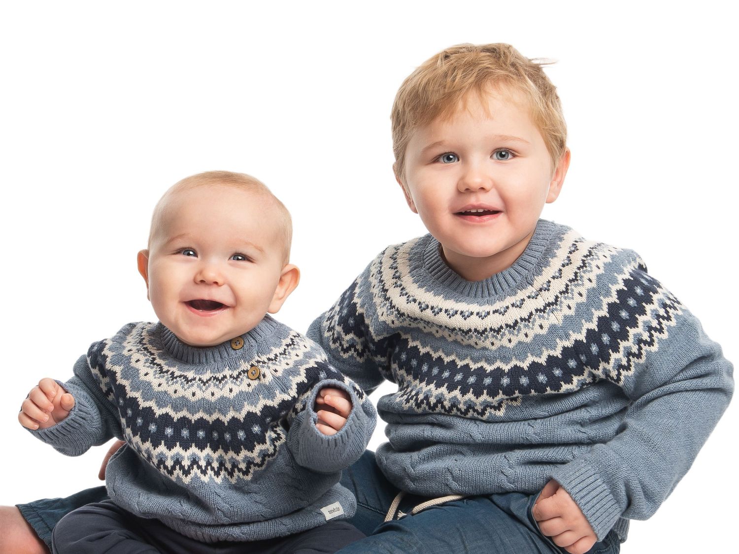Children wearing matching gray and navy Nordic sweaters in sequence of playful expressions.