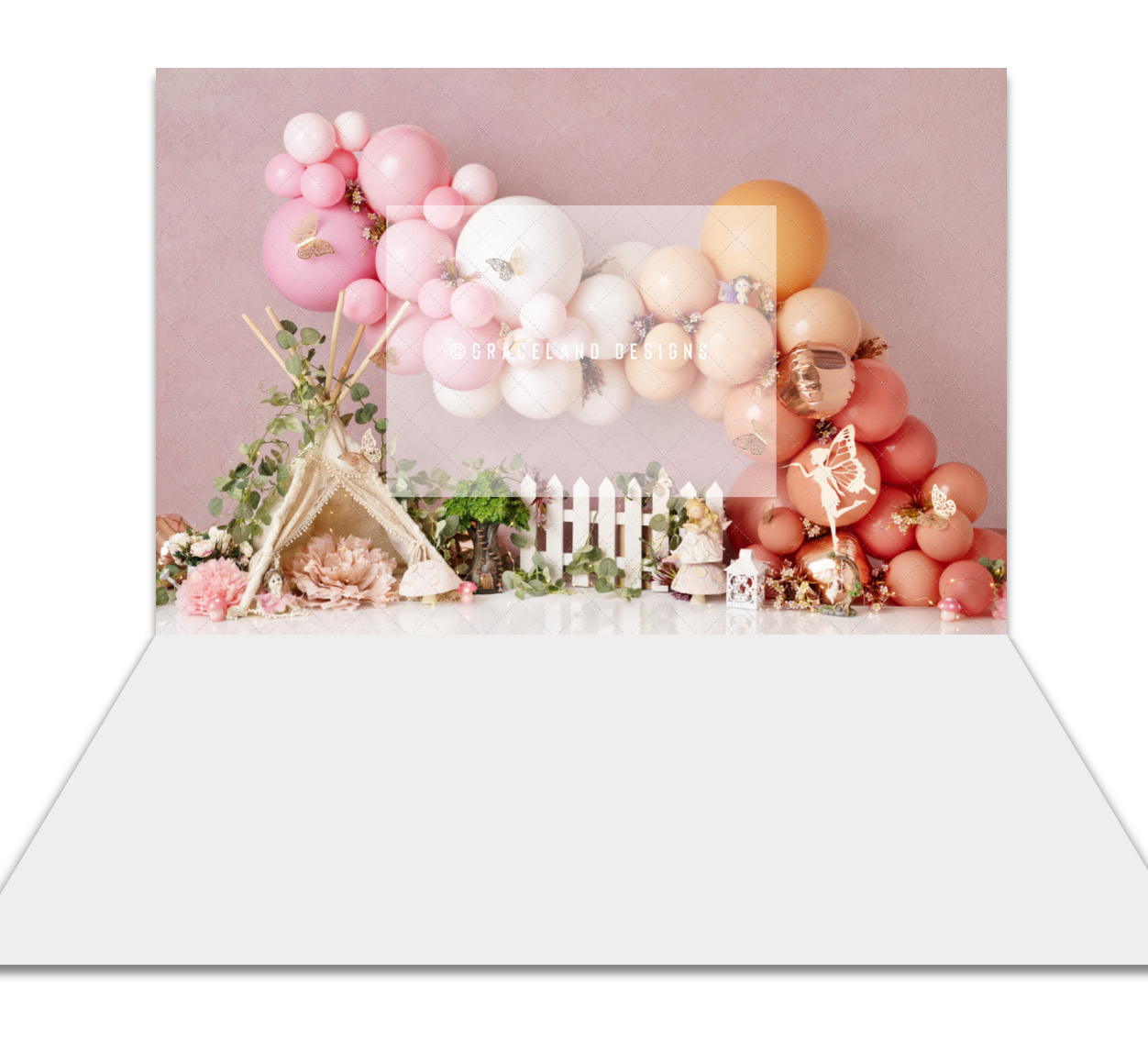 Pink balloon garland birthday backdrop with floral decorations, white picket fence, and boho teepee for cake smash photography.
