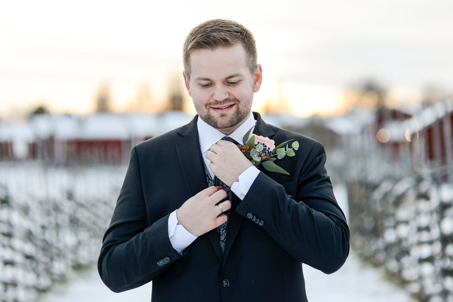 Groomsmen in formal attire pose playfully in the snow.