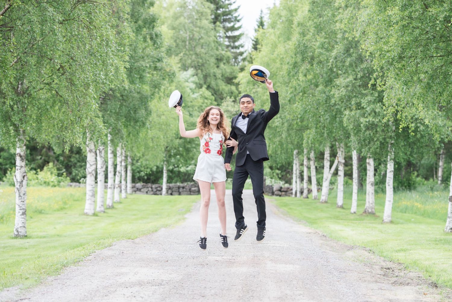Wedding couple walking down a tree-lined path surrounded by white birch trees.