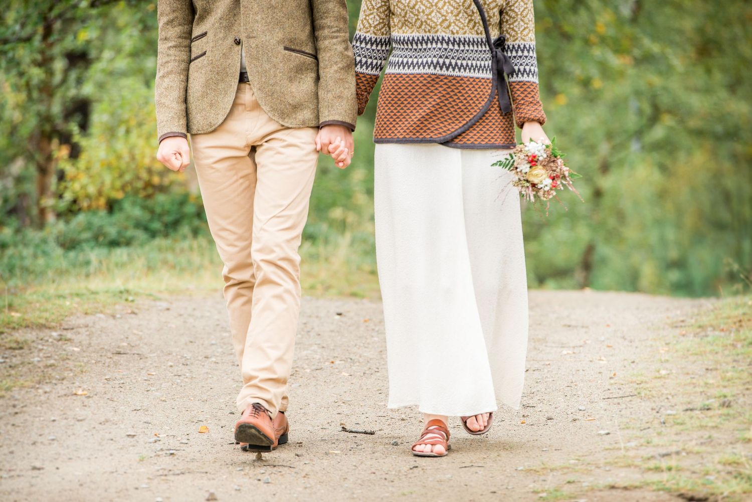 A couple strolls together through a lush garden path surrounded by greenery.