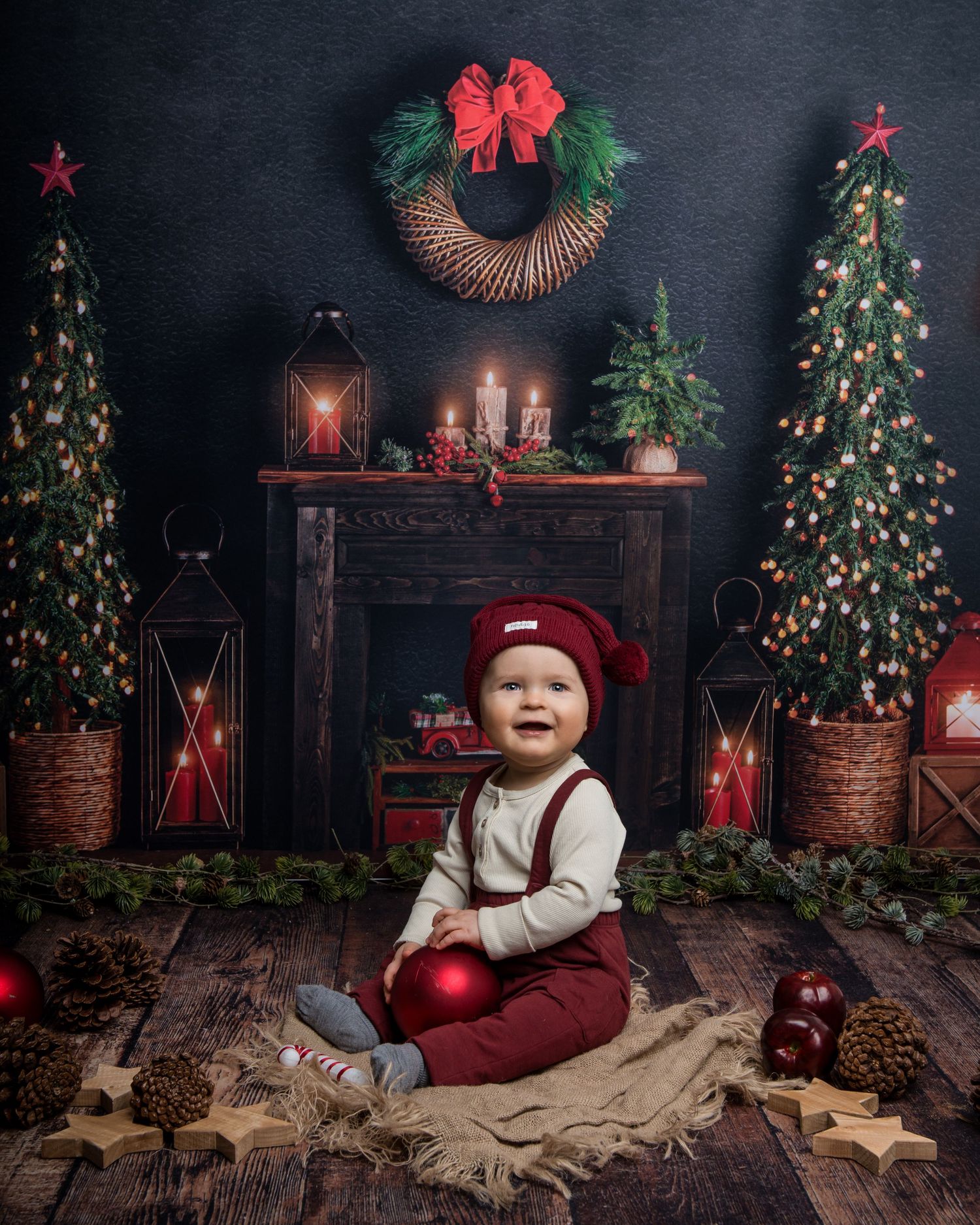 Holiday photo setup with Christmas trees and rustic decorations against dark backdrop.