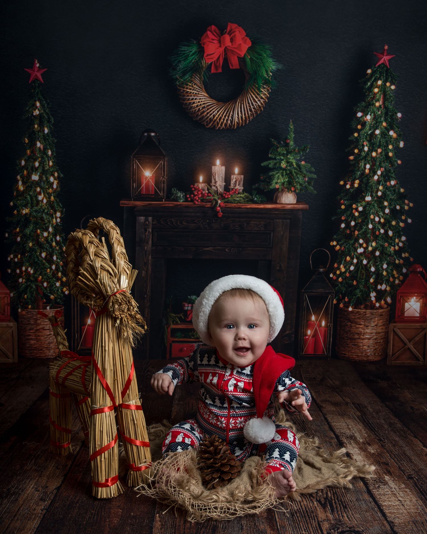 Christmas photo setup with hay bales, red ornaments and decorated trees in rustic setting.