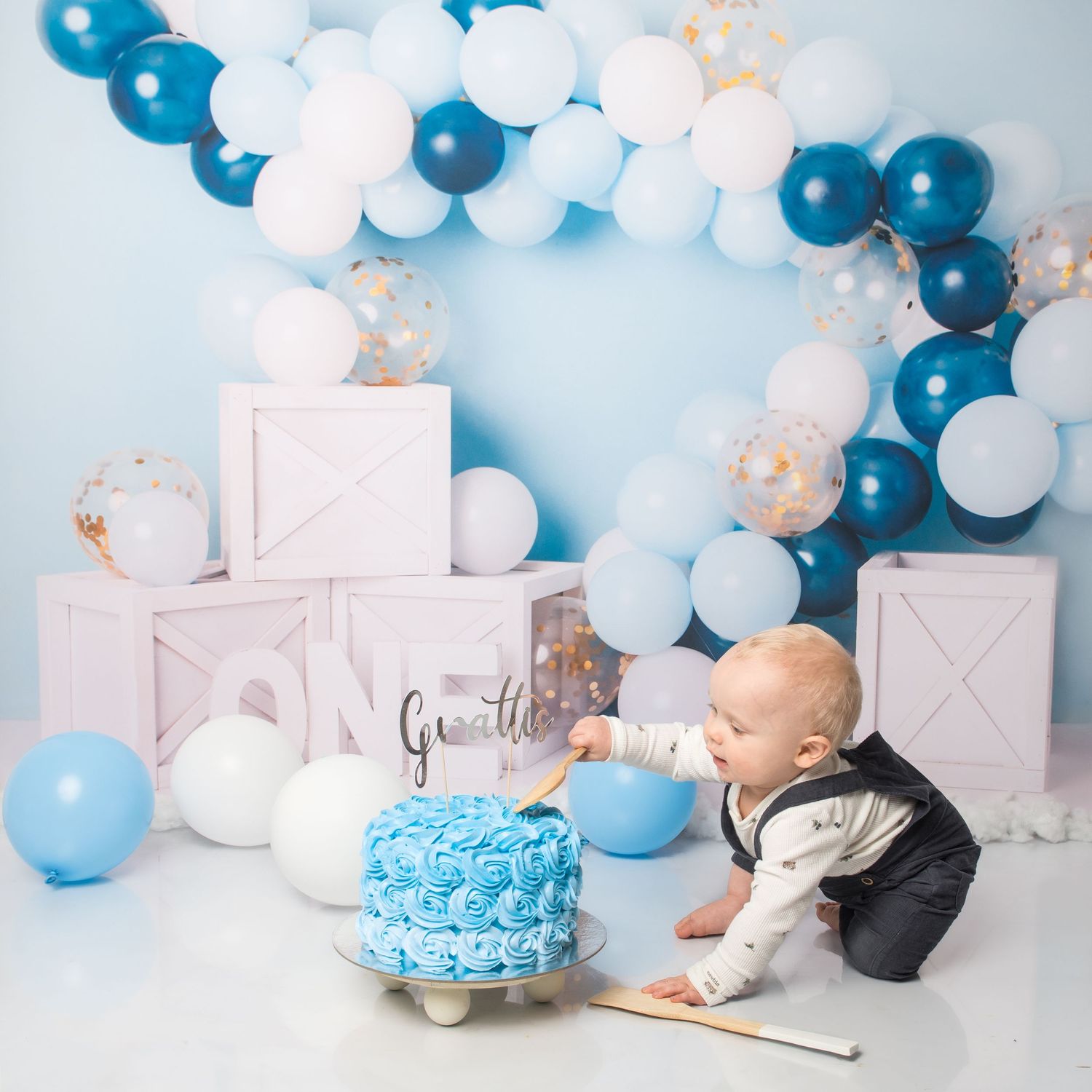 First birthday photo setup with blue balloons and cake smash aftermath.