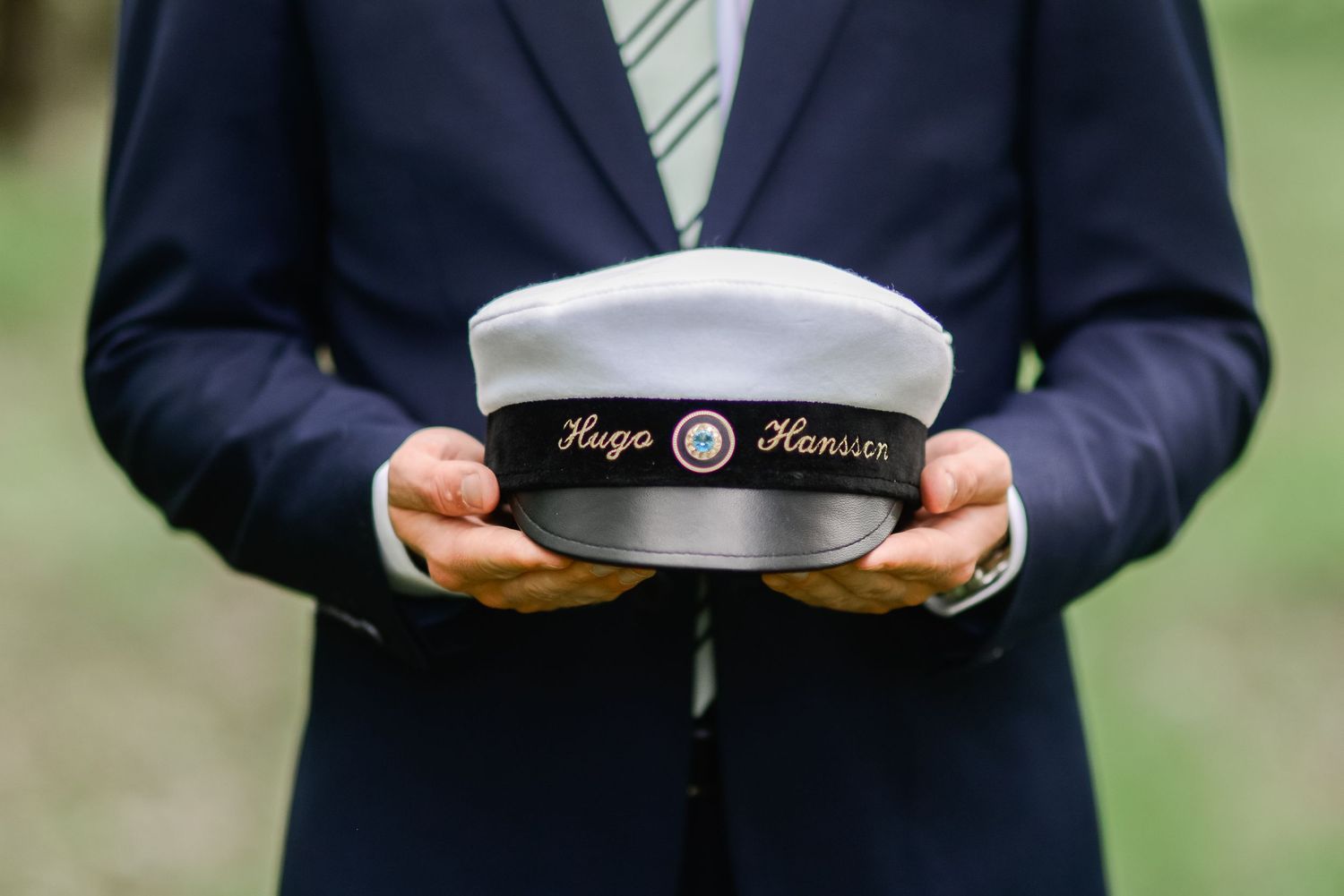 Close-up detail of a white captain's hat with navy trim and striped tie.