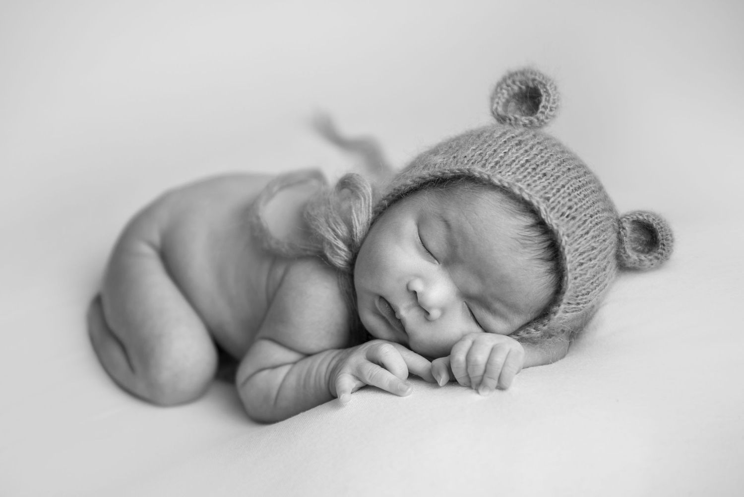 Artistic black and white photo of sleeping newborn with knit accessories.