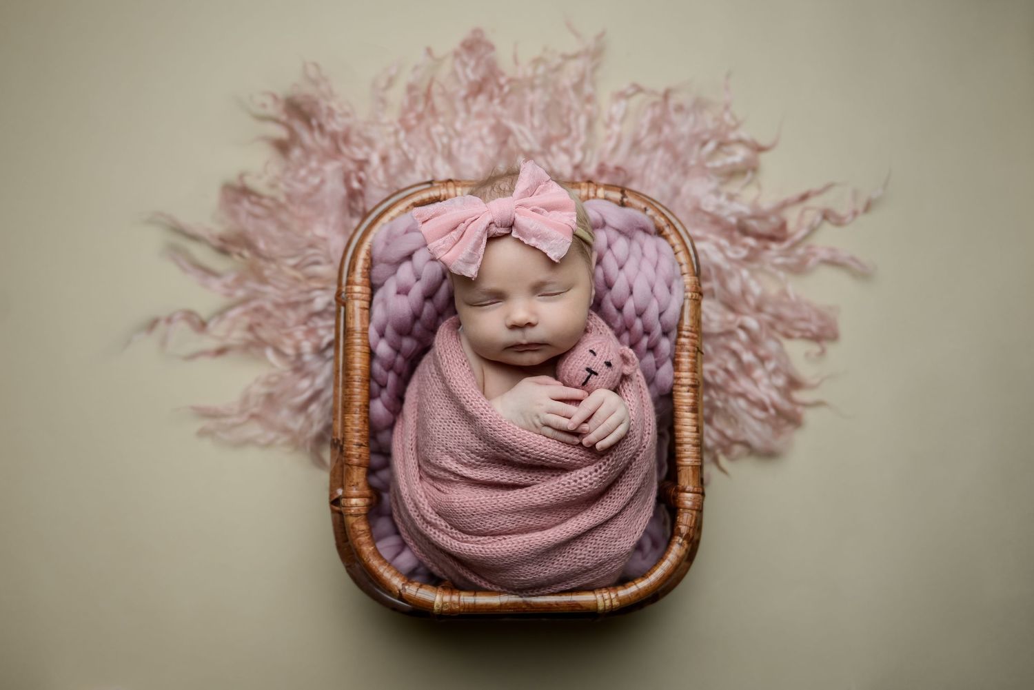 Newborn photography series with baby in pink wrap against neutral backdrop.