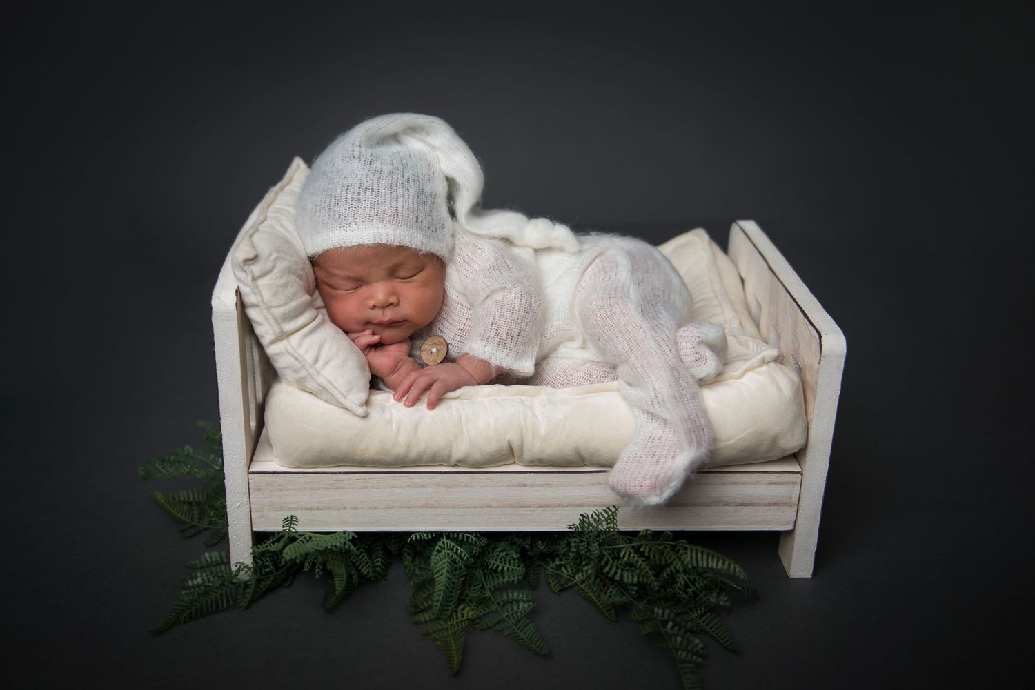 Professional newborn photography on white miniature daybed with delicate styling.