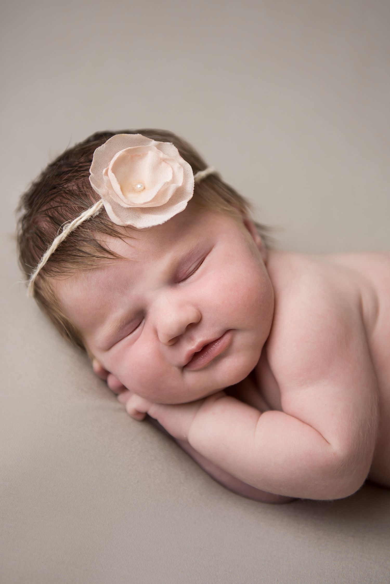Artistic newborn portraits with delicate pink flower accessory.