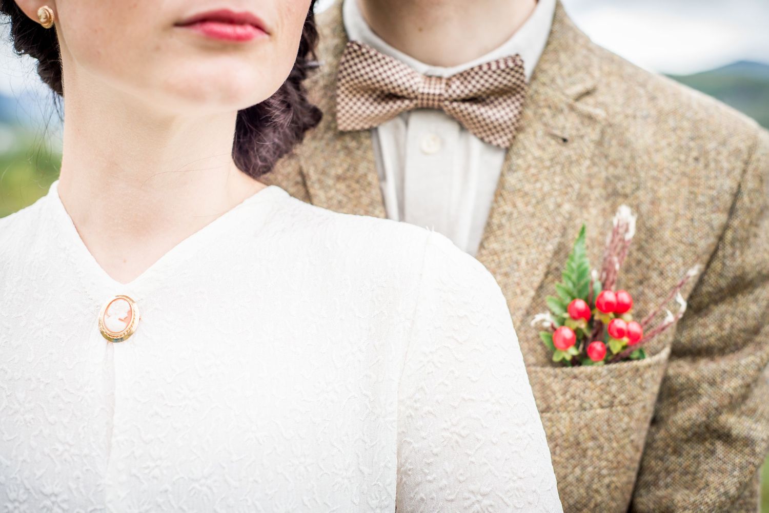 Wedding portrait featuring a couple in white dress and tweed suit against a soft background.