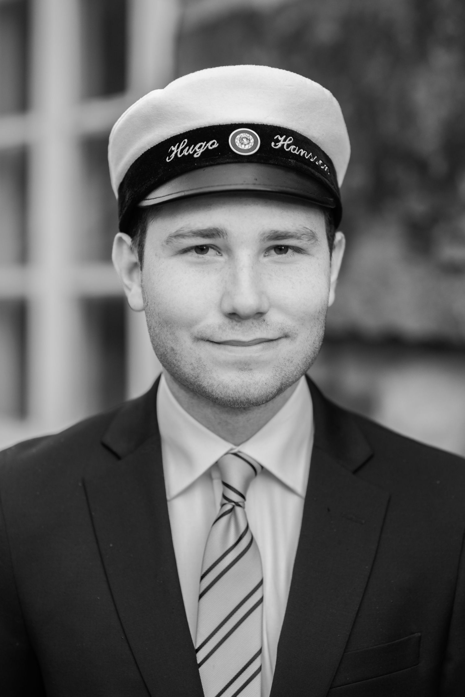 A series of black and white portraits showing someone in a suit and nautical cap.