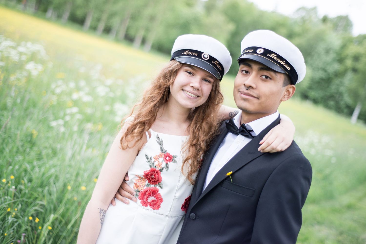 Romantic graduation photos of a couple embracing in a sunny meadow with birch trees.