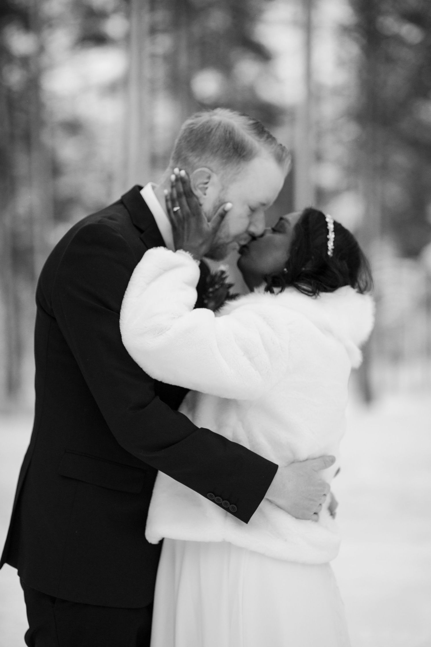 An intimate embrace between newlyweds in a snow-covered forest setting.