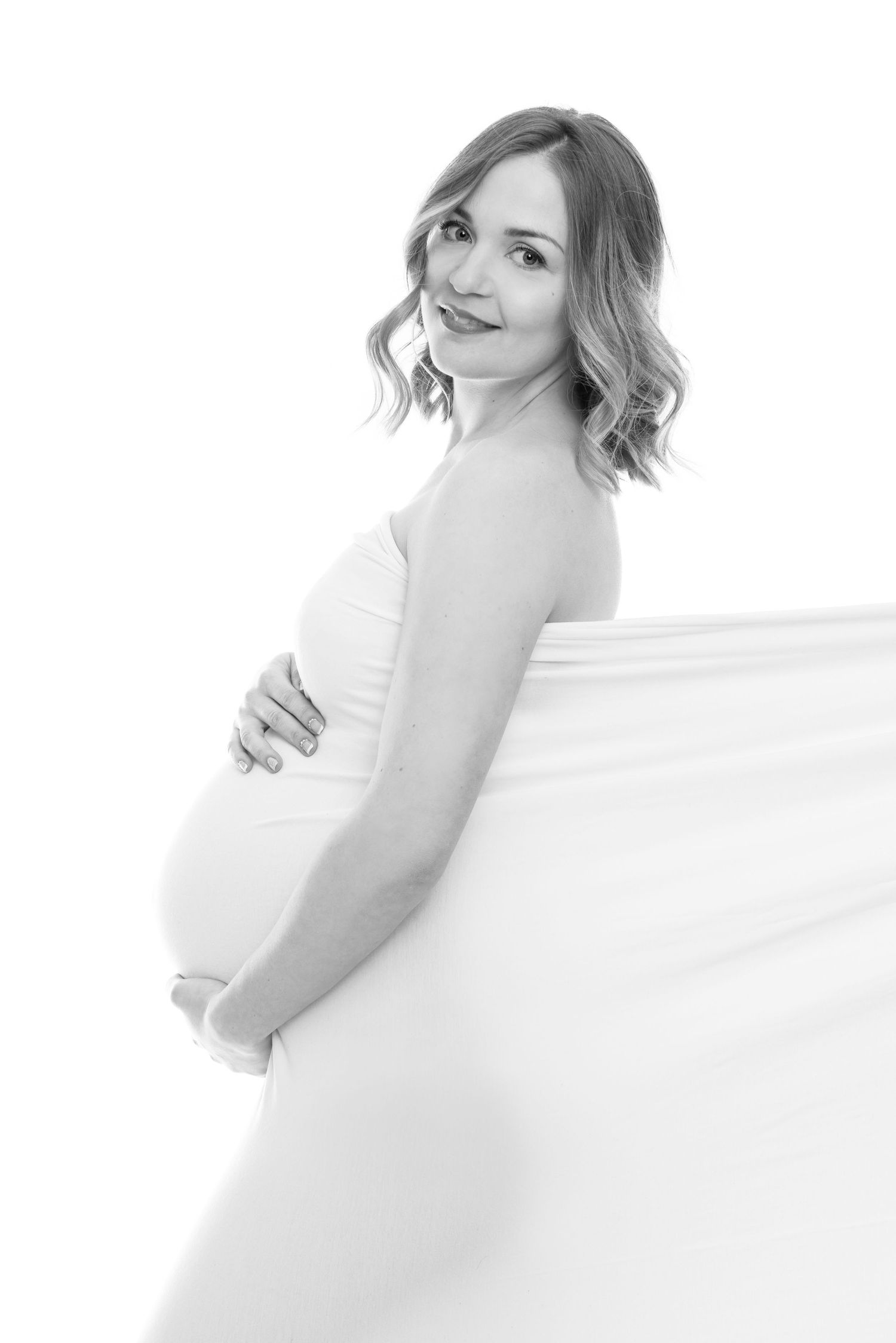 High-key maternity portrait series in white against light background.
