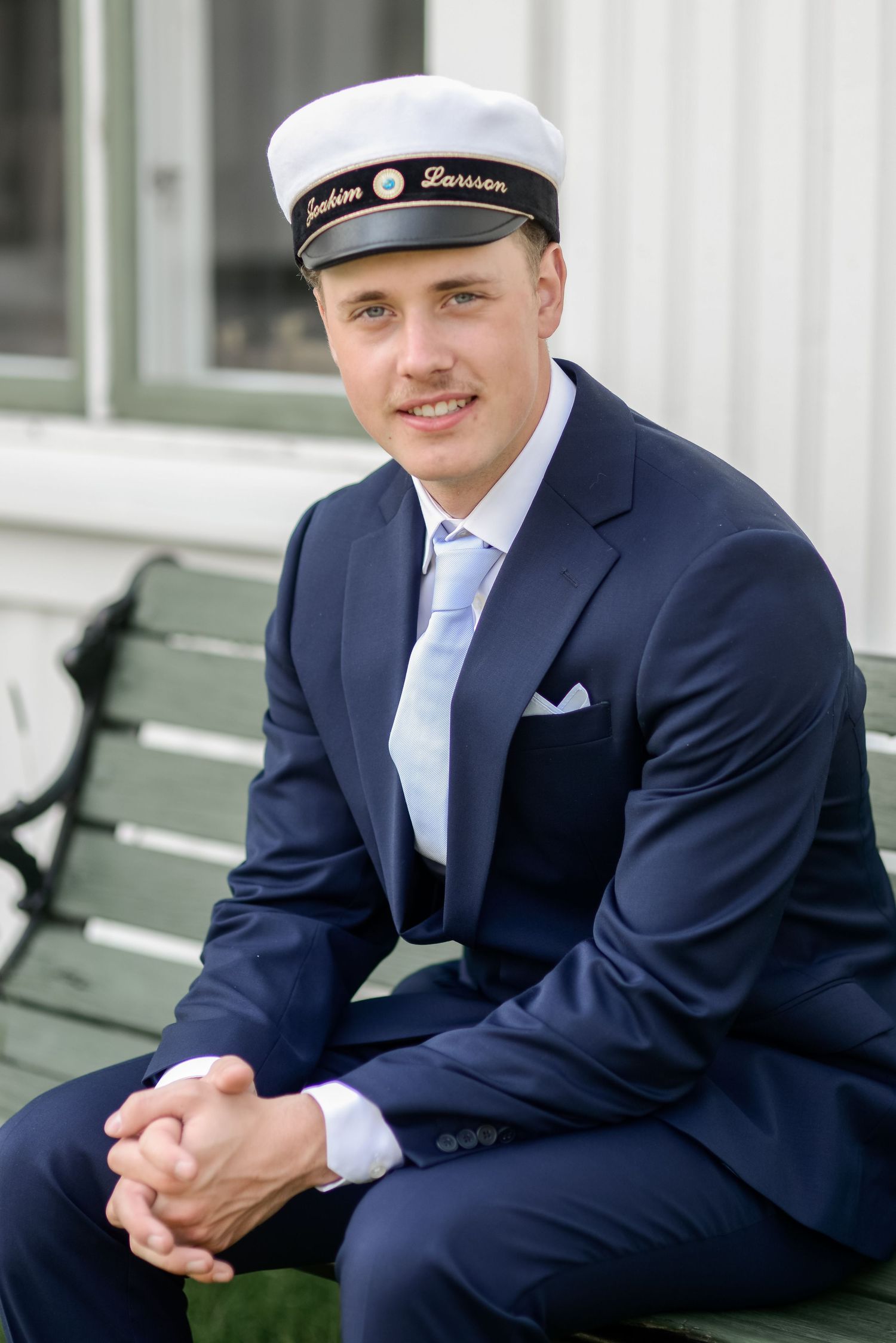 Formal portraits taken on a white porch with someone in navy attire and sailor cap.