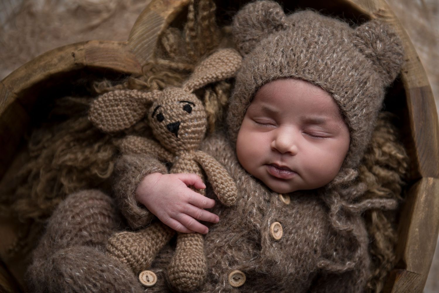 Artistic newborn photography featuring cozy brown knitted accessories and natural lighting.