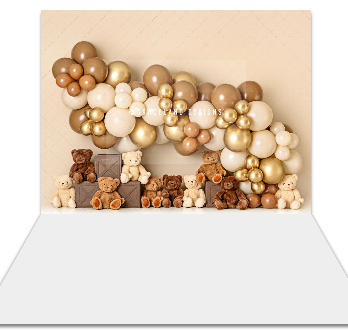 Teddy bear party backdrop with gold, cream, and brown balloon garland arch and cute stuffed bears on a beige background.