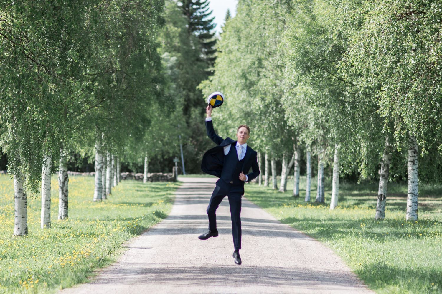 Tree-lined path with distant figure in formal attire walking.