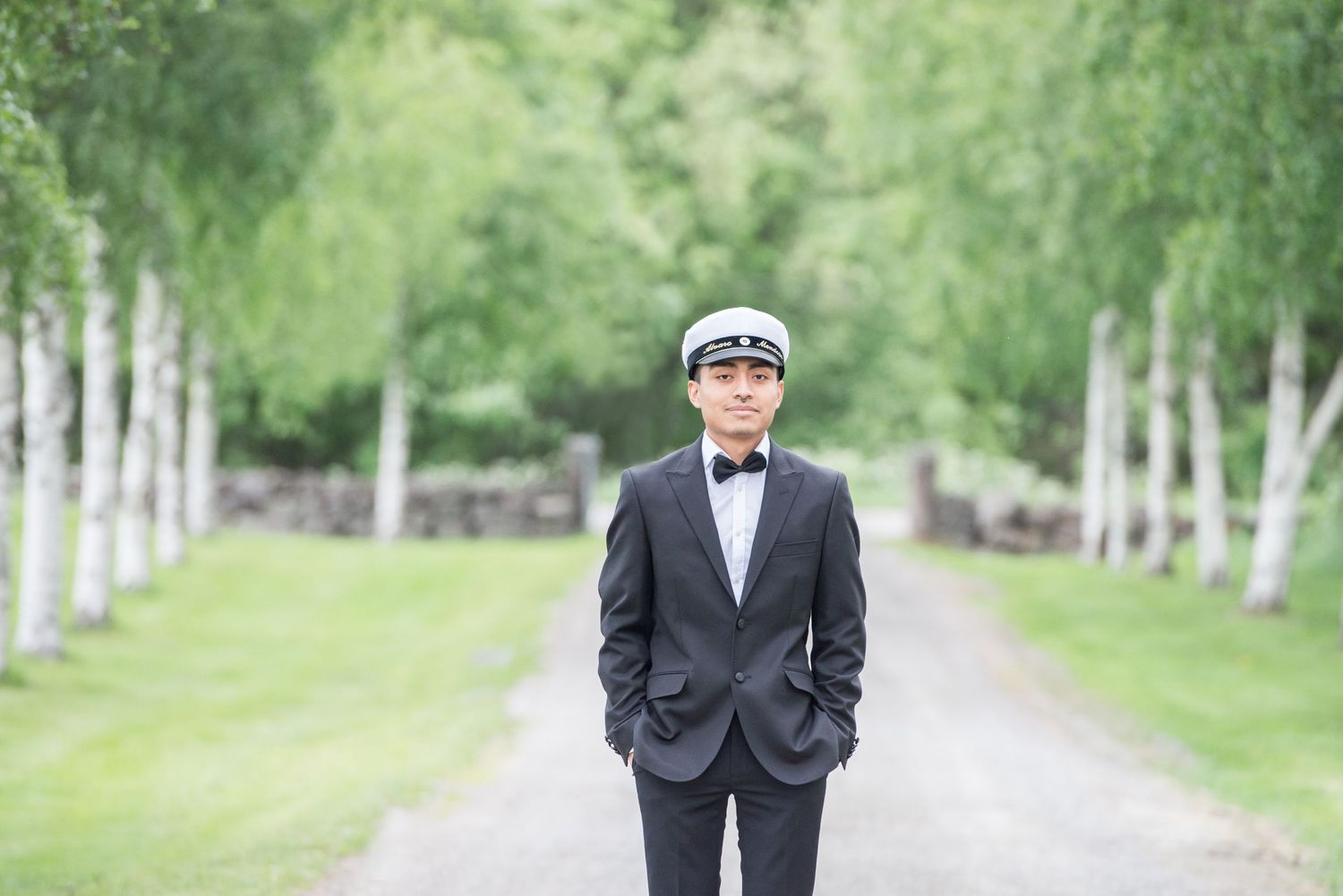 Elegant couple in formal attire walking along a scenic birch tree path.