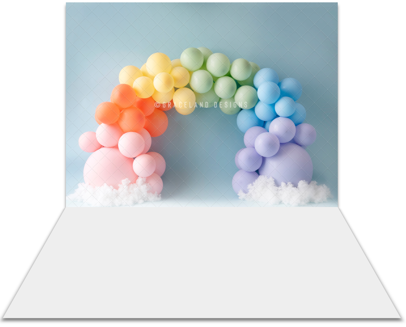 Colorful pastel rainbow balloon arch backdrop with white clouds on a light blue background for party photography.