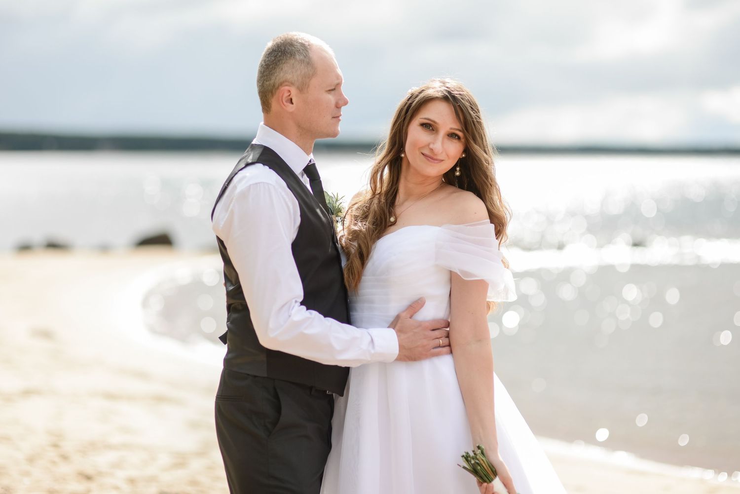 Beach wedding photography with sparkling water and soft natural lighting.