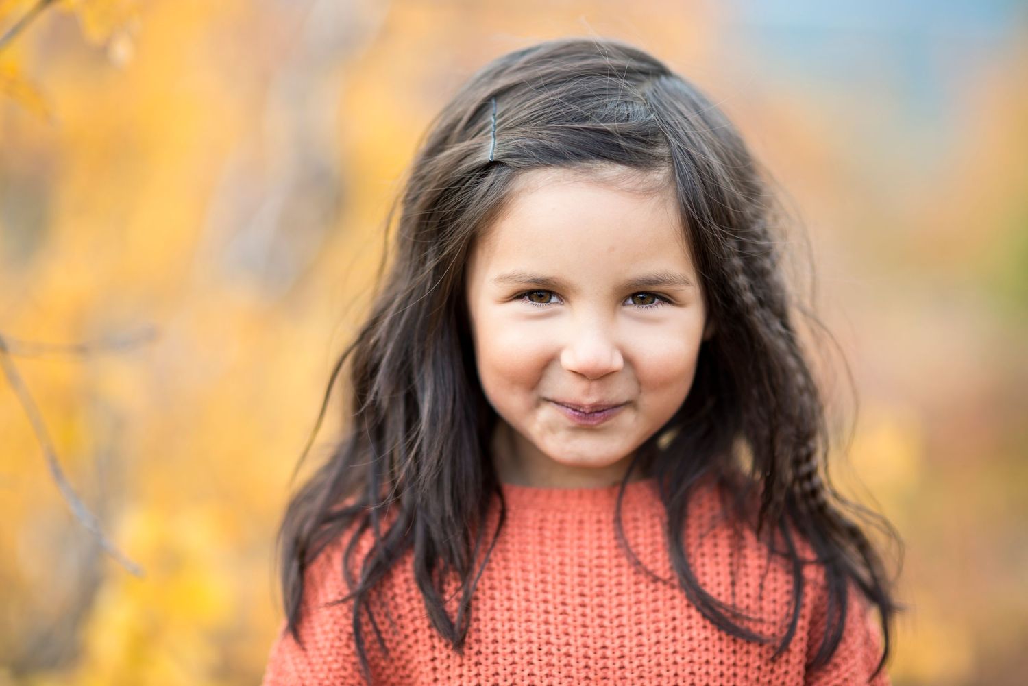 Portrait with warm autumn colors in background and coral knit sweater in foreground.