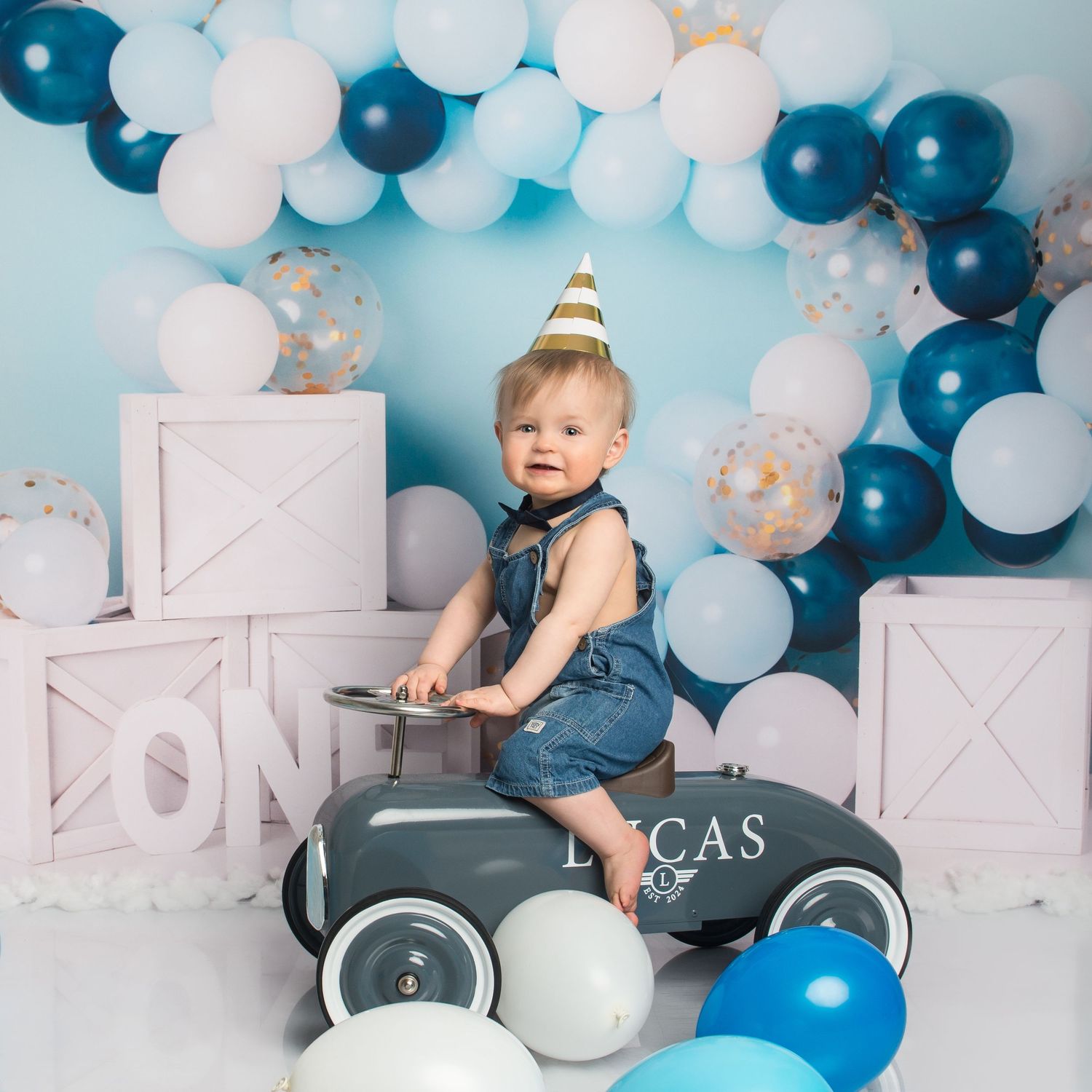 First birthday setup with blue and white balloons, white boxes, and modern decorations.