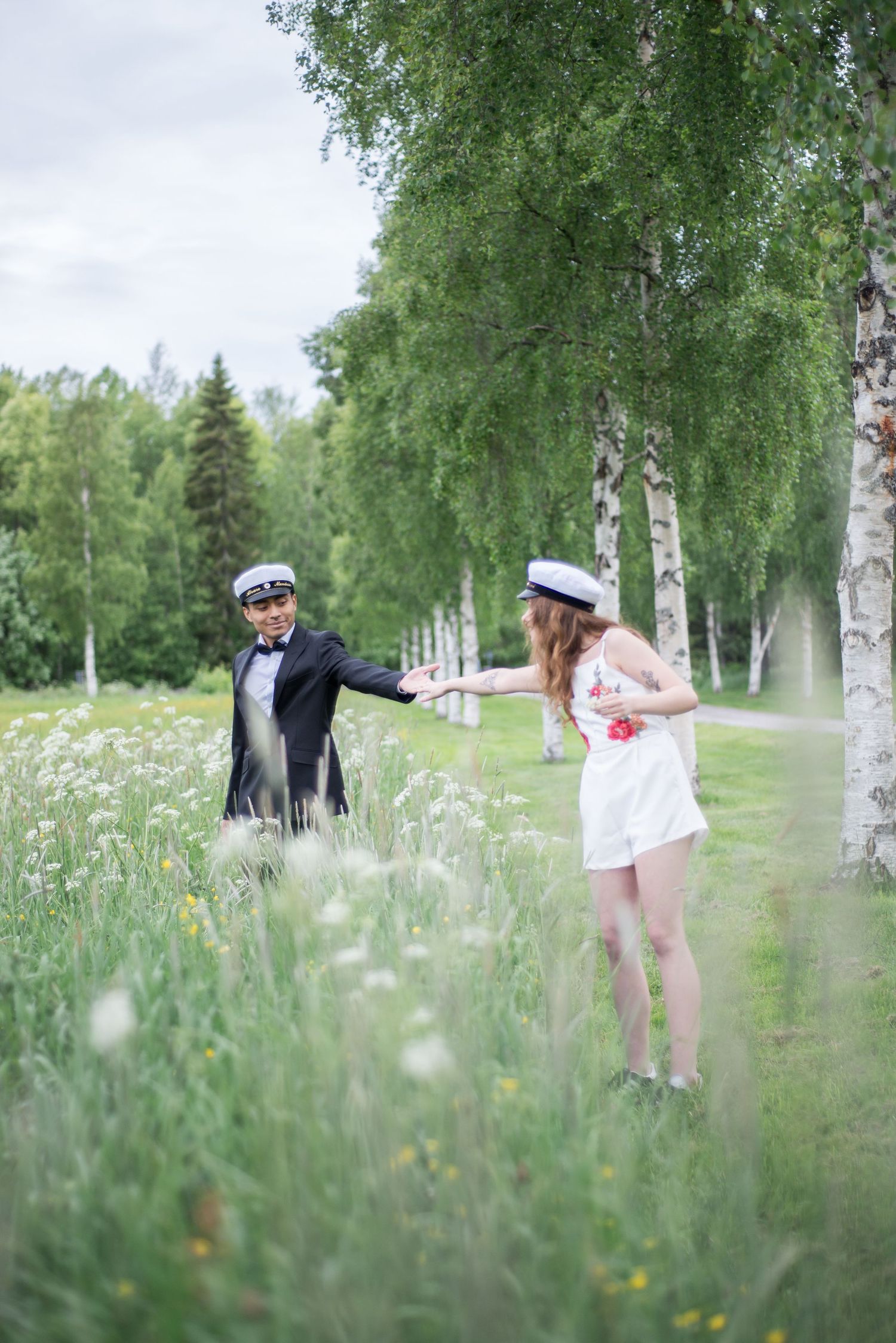 Artistic photo of a couple in a meadow with birch trees and wild daisies.