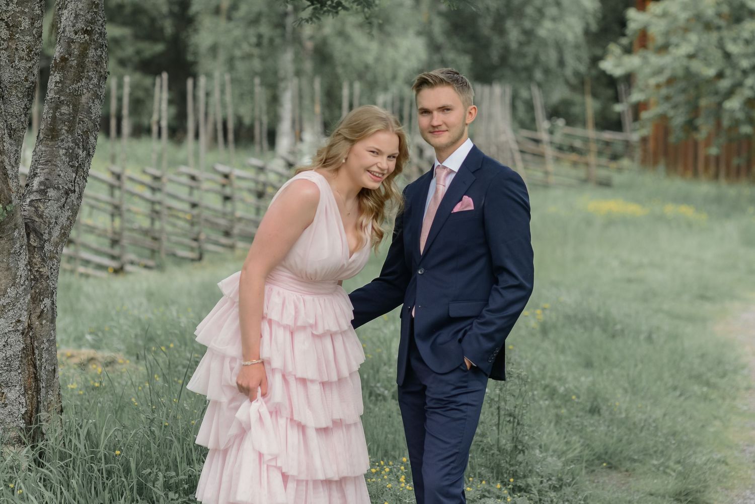 A couple shares a candid moment while walking along a wooded path.