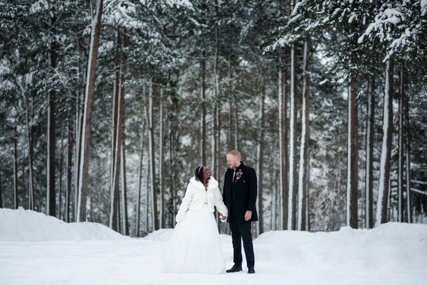 Snowy forest path with elegant winter wedding decorations and lighting.