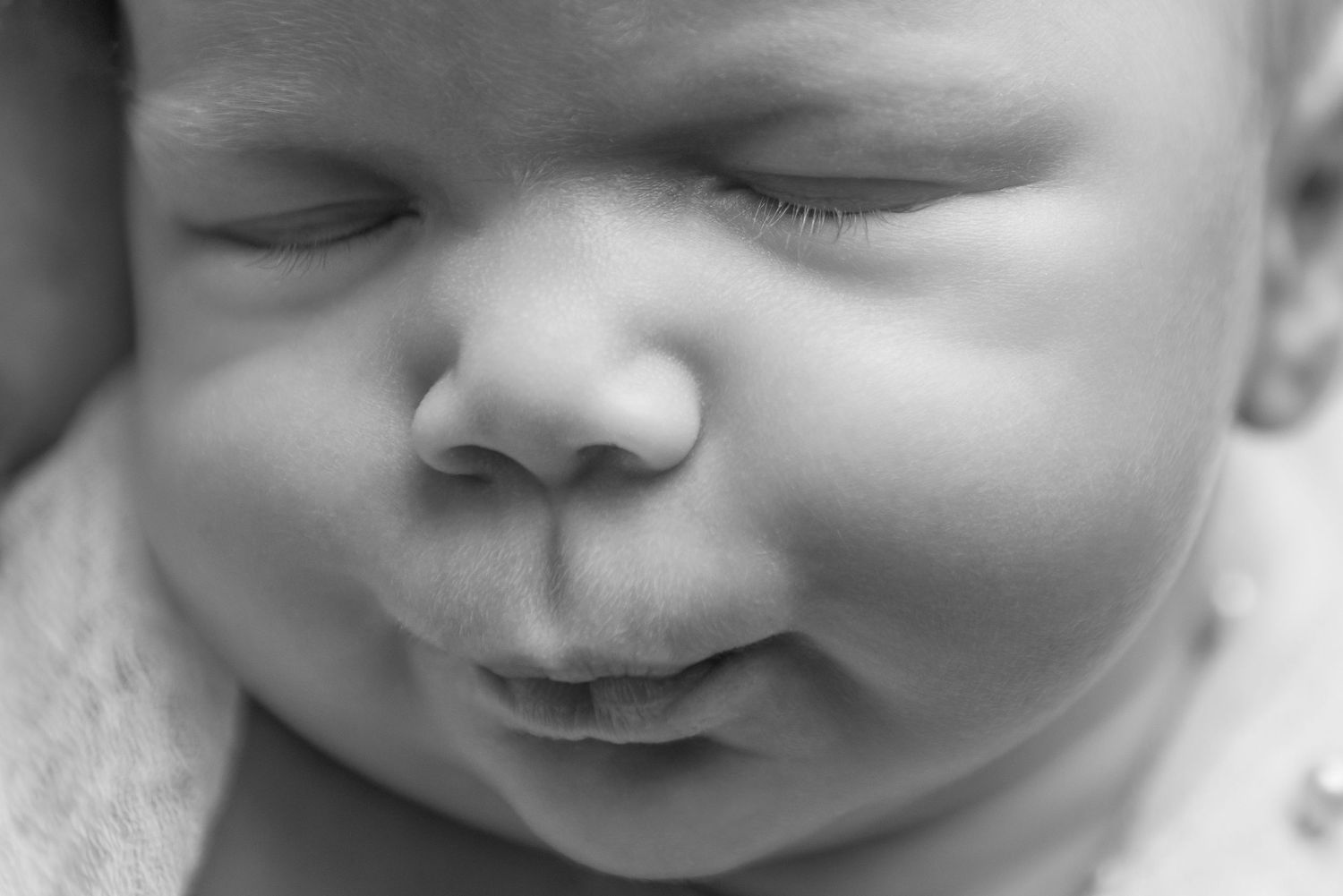 Close-up black and white portrait showing gentle newborn expressions.