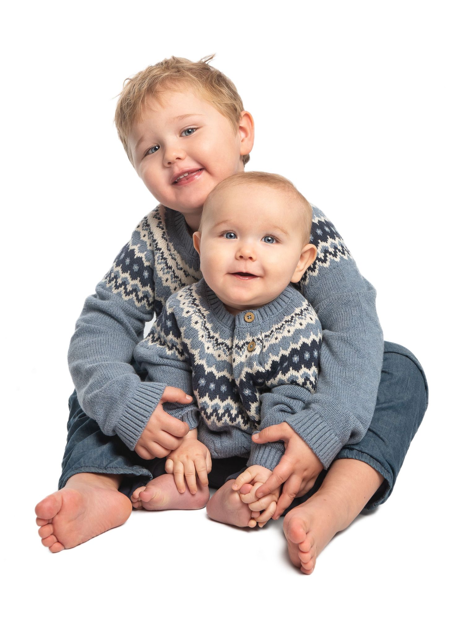 Baby in traditional Nordic sweater posing on white background.