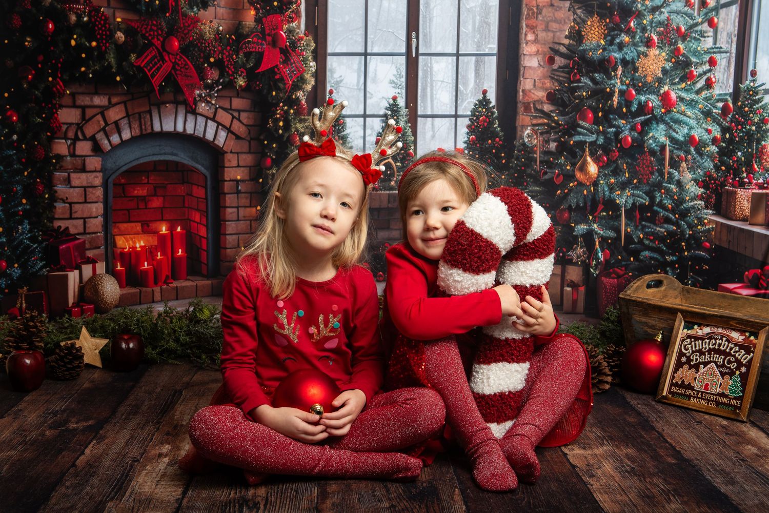 Christmas photo studio setup with red brick wall, decorated trees, and festive lighting.