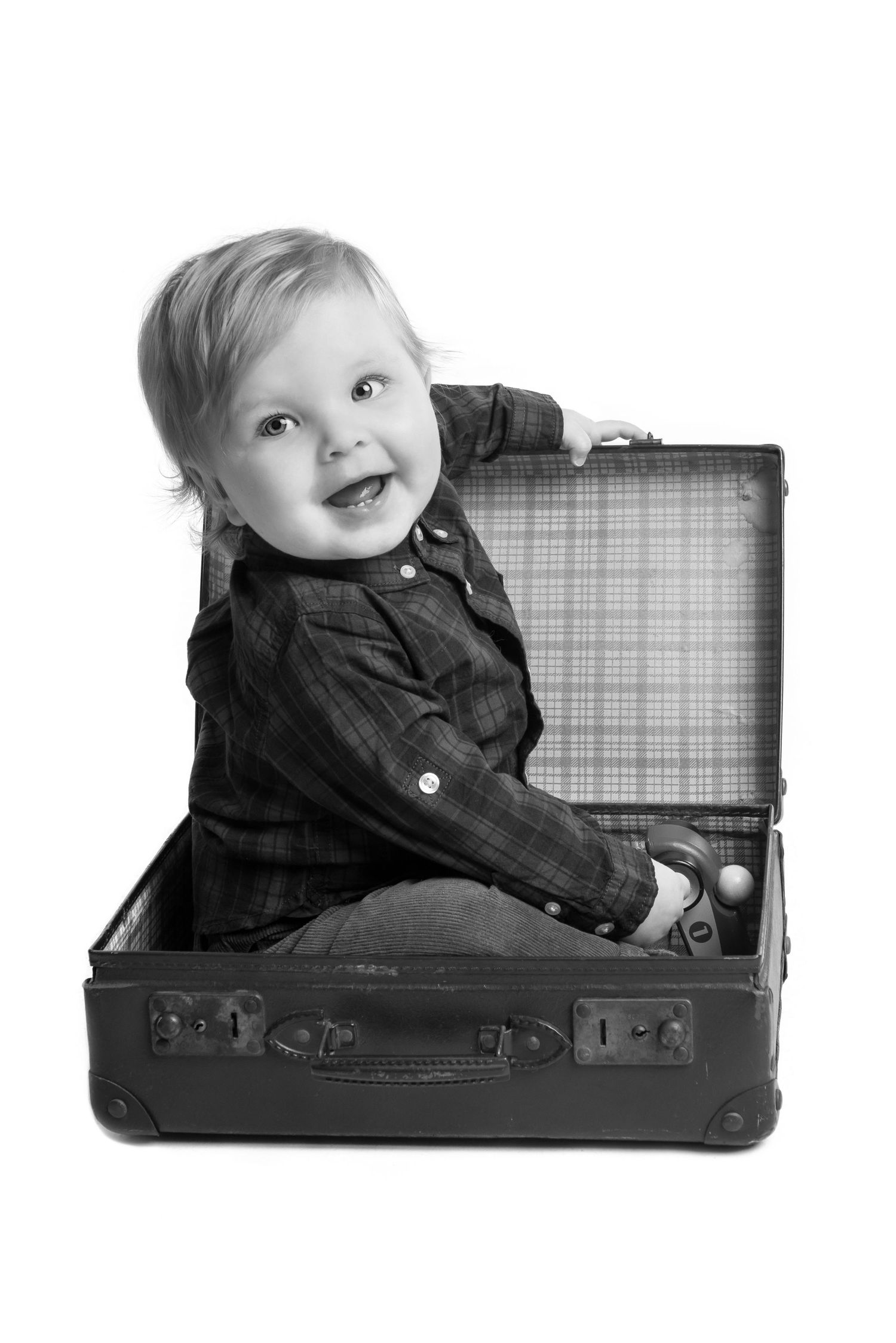 Creative black and white photo sequence of baby playing inside vintage suitcase.