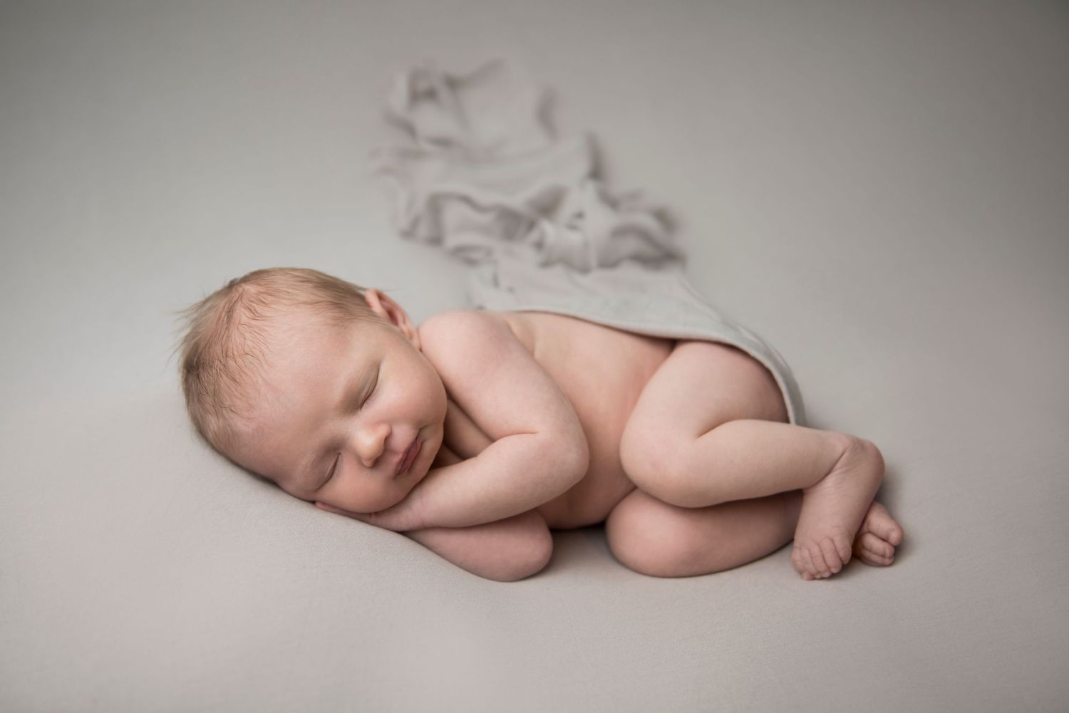 Peaceful sleeping newborn posed on textured backdrop during professional photoshoot.