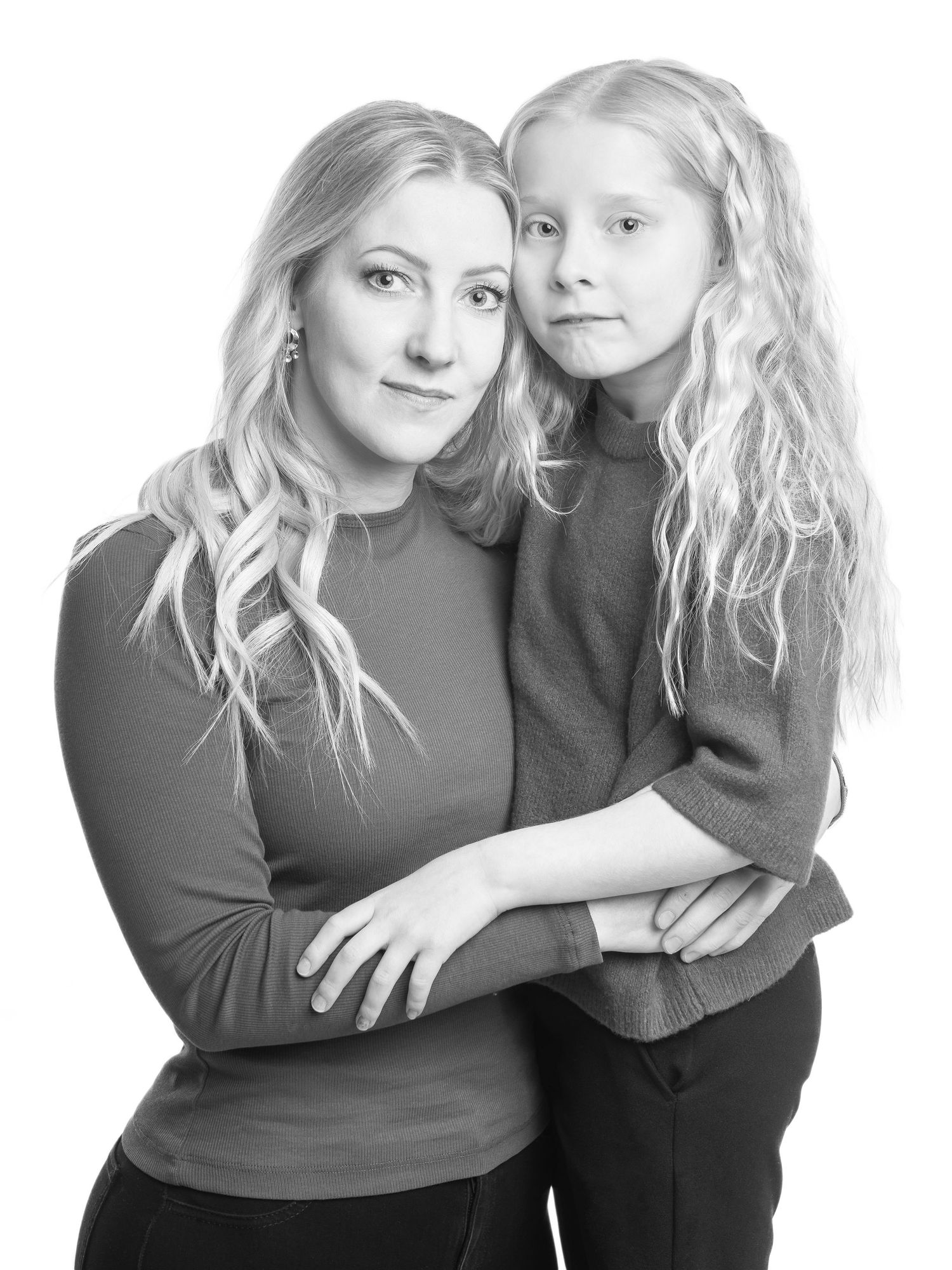 Black and white studio portrait series showing intimate mother-daughter embrace.