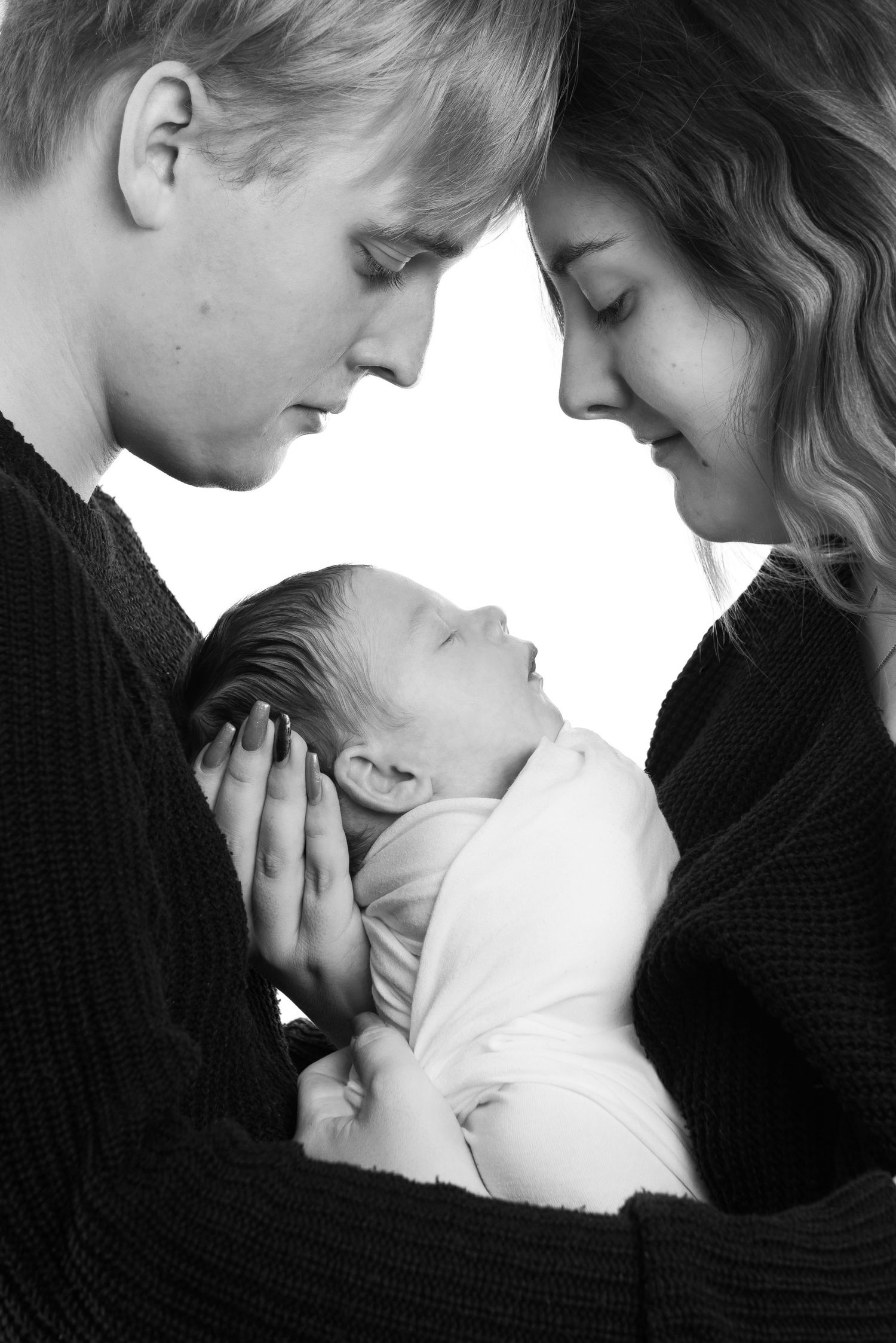 Black and white portrait of tender family moment with newborn baby.