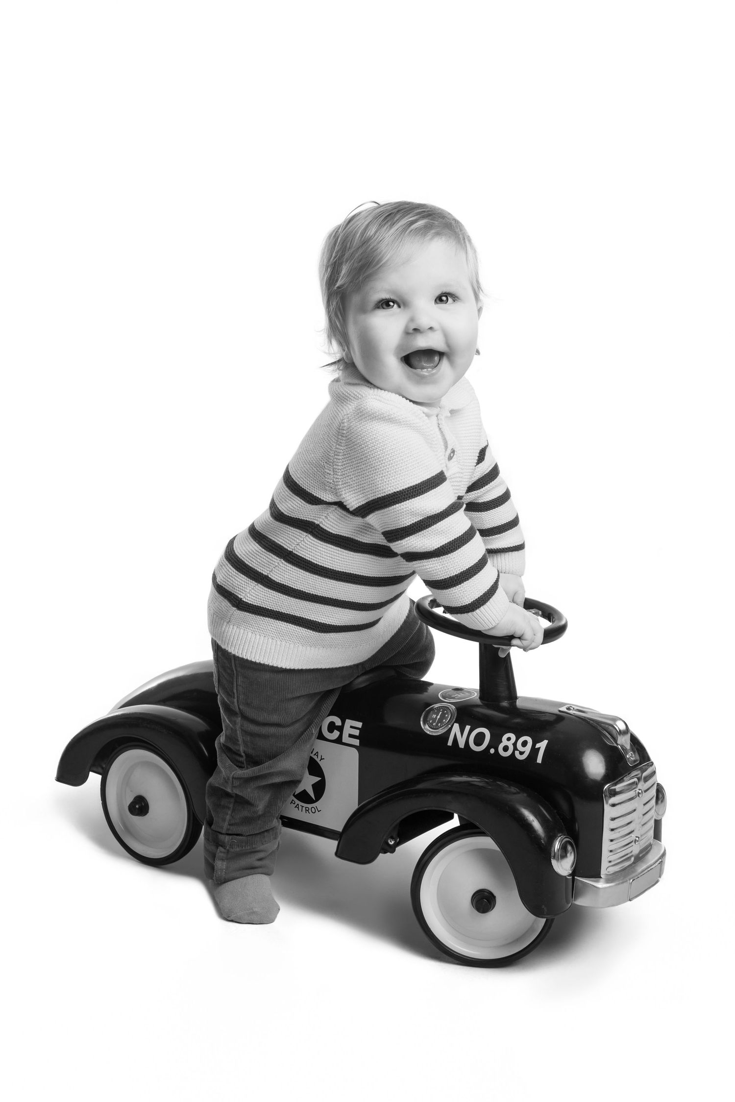 Baby riding retro-style toy police car in black and white progressive motion shots.