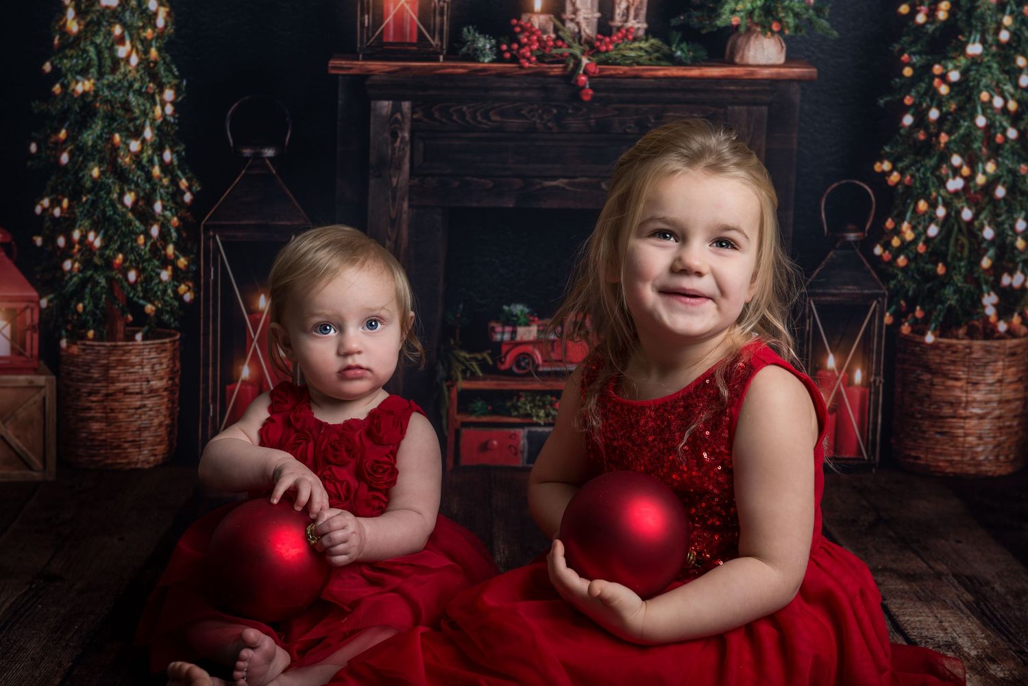 Christmas portrait setup with multiple decorated trees, red lanterns and festive decor on wooden floor.