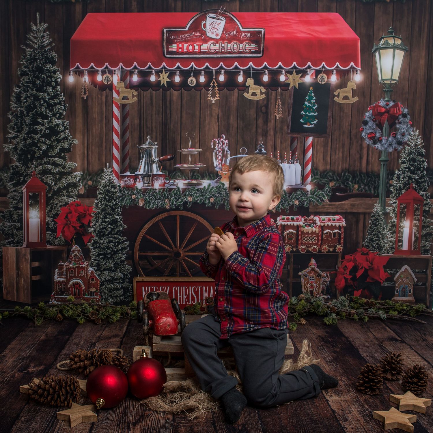 Rustic Christmas market themed photo setup with red storefront, decorated trees and vintage elements.