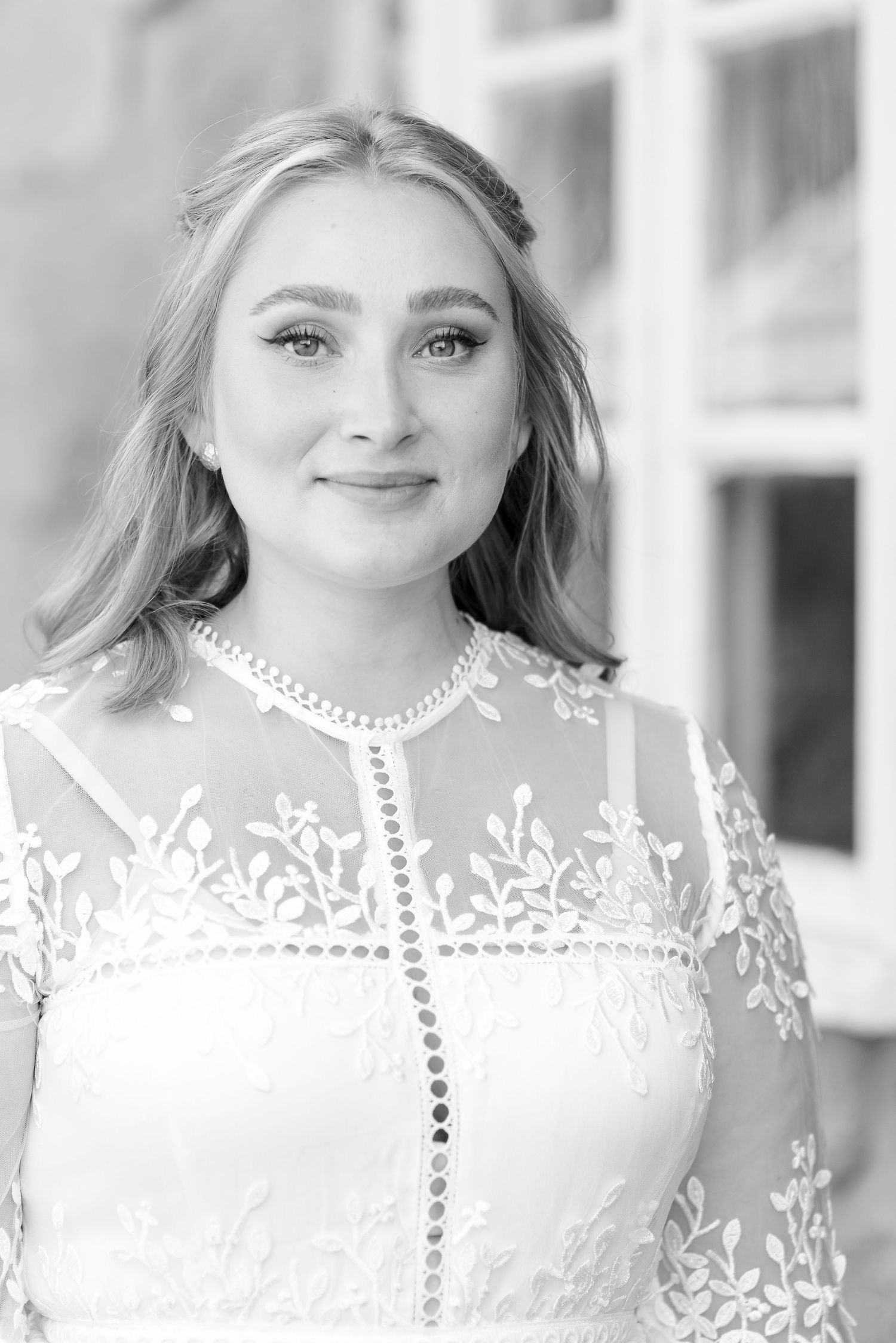 Elegant bridal portrait in white lace dress with delicate embroidery details.