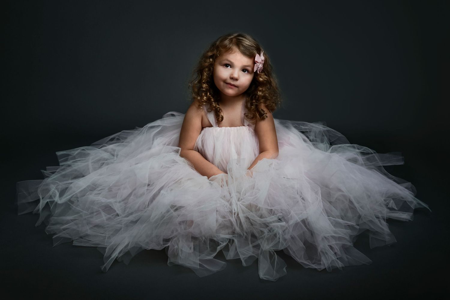 Artistic portrait session with flowing white tulle dress against dark background.