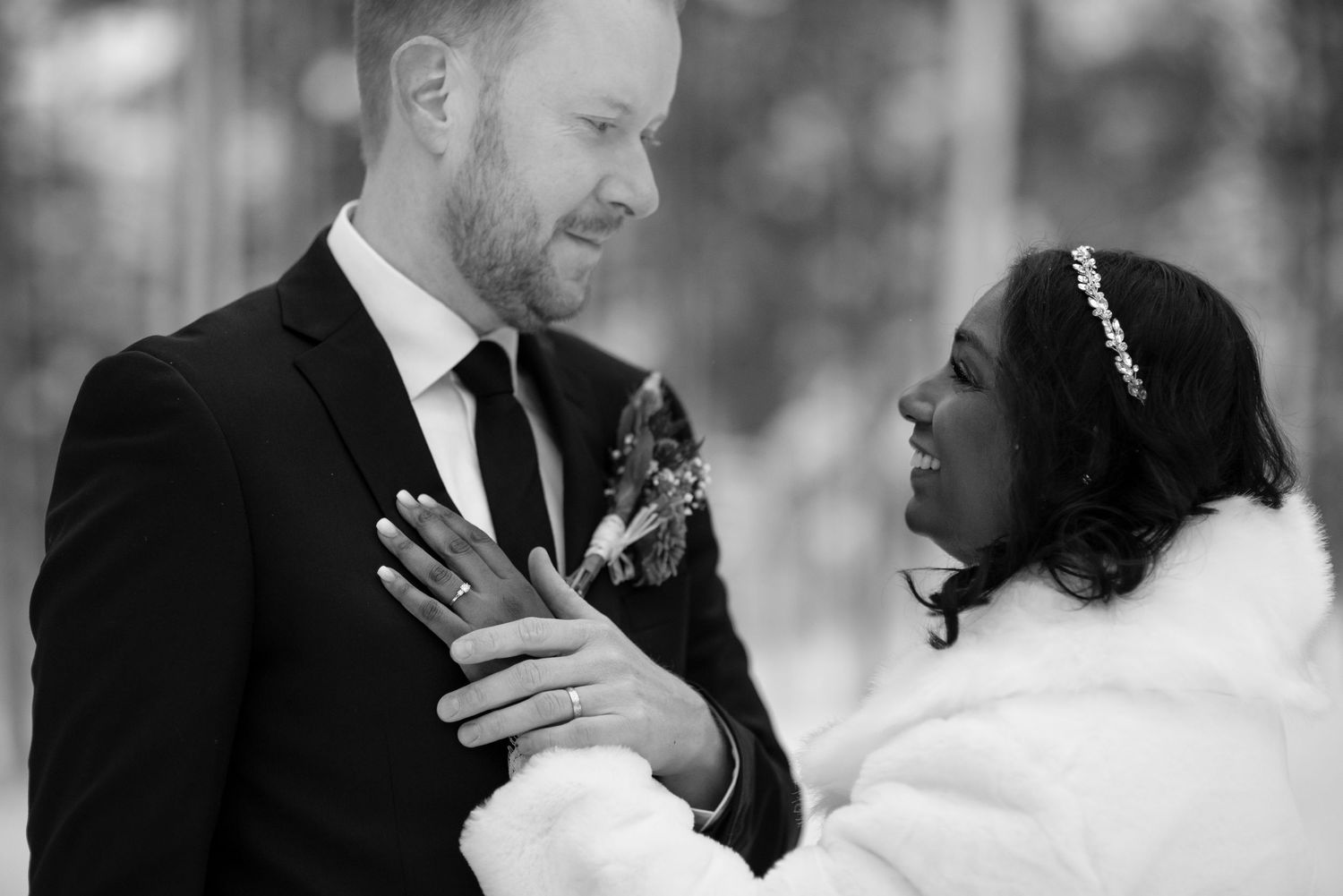 A romantic winter wedding moment captured in black and white against a forest backdrop.