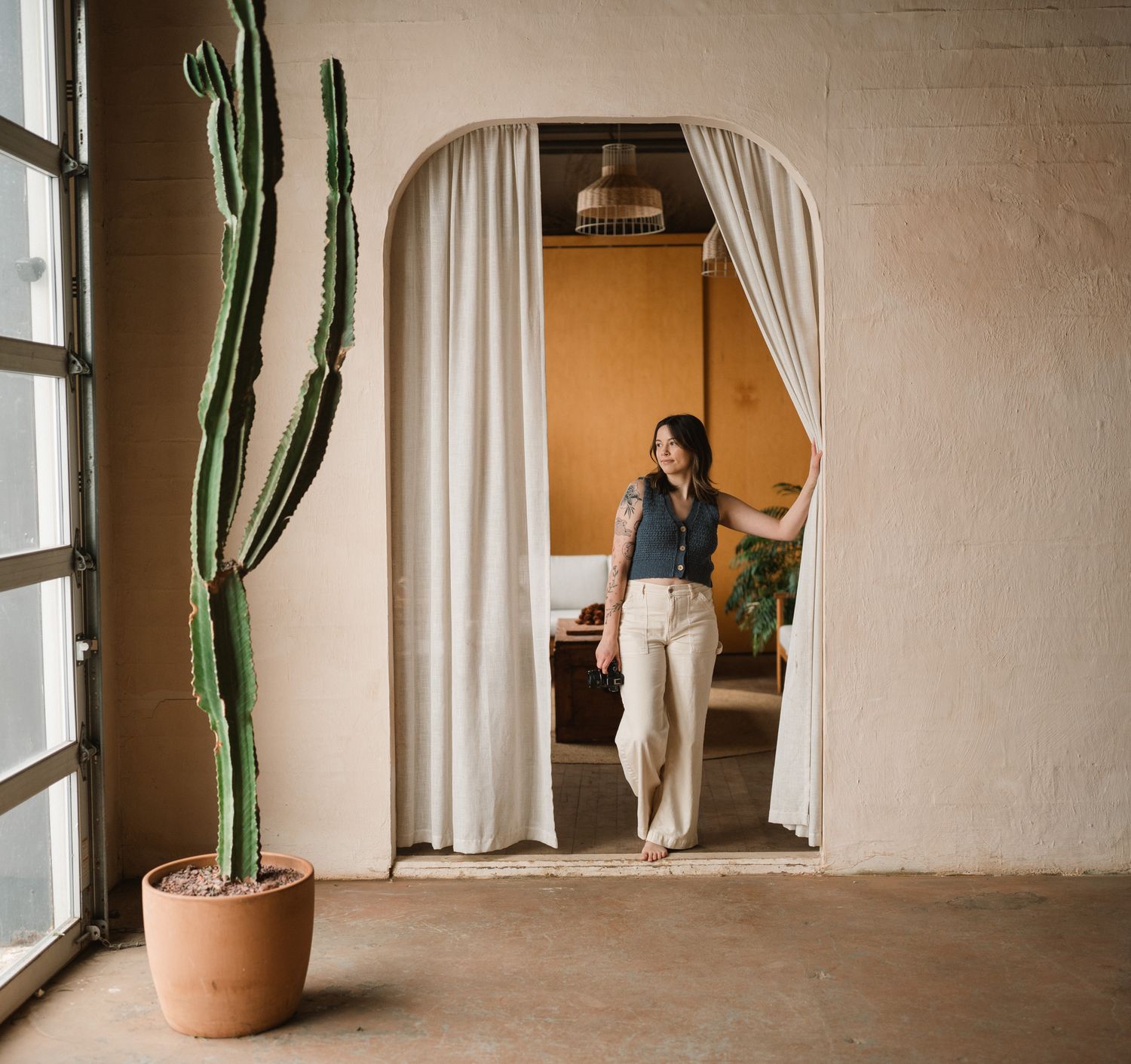 photographer standing in earthy toned space next to cactus.