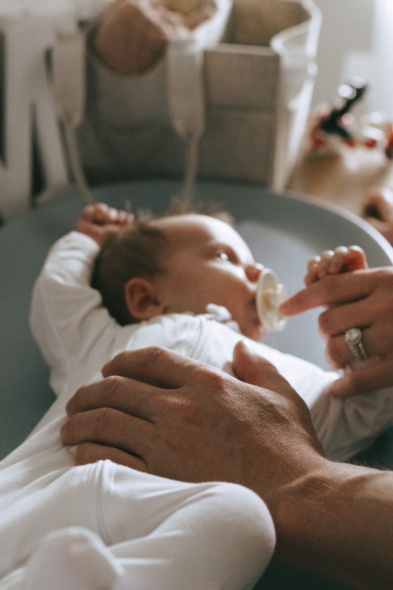 Dad and mother's hands resting gently on newborn baby.