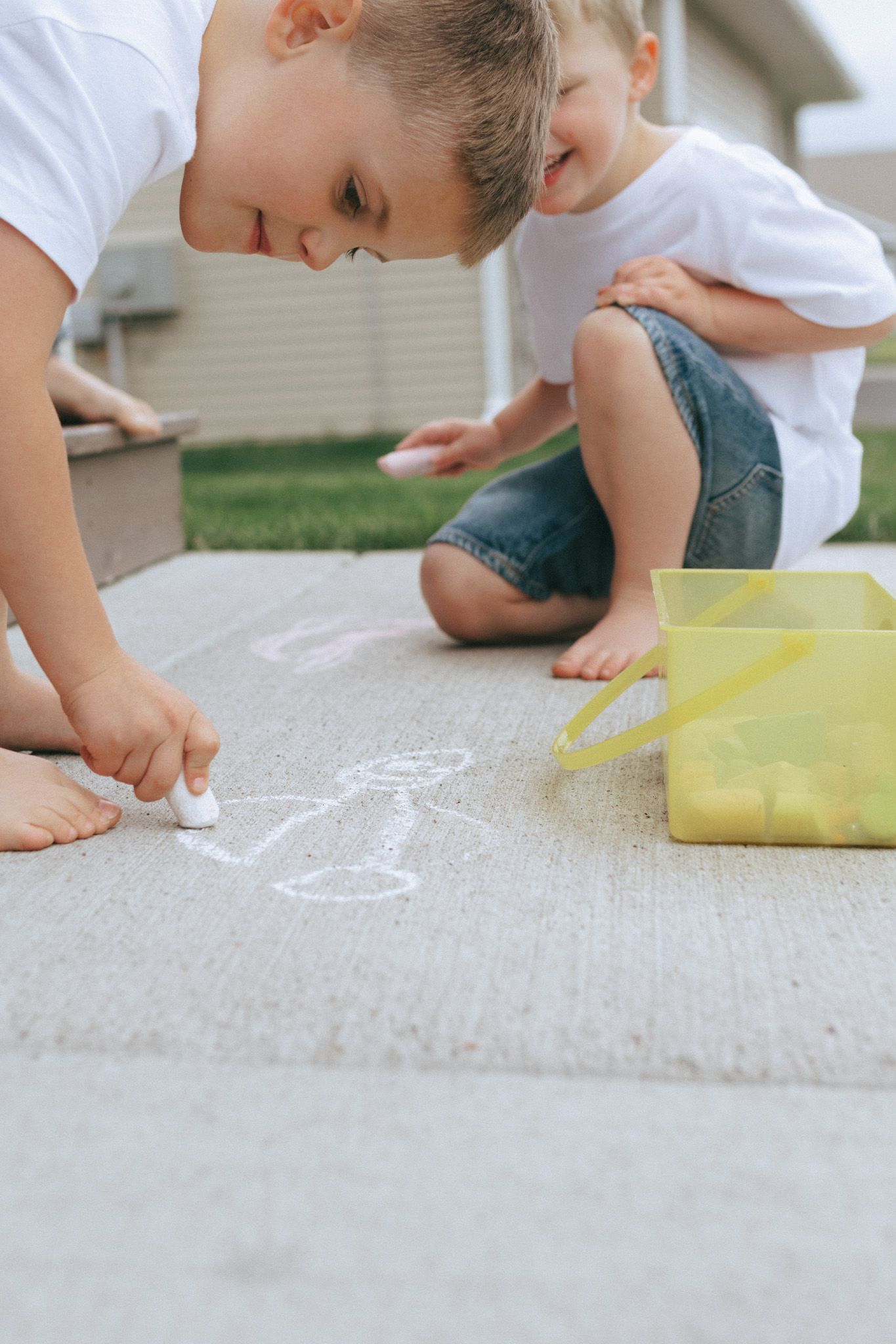 Two boys playing with chalk outside.