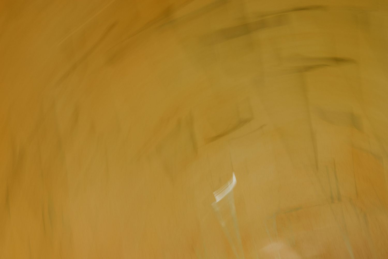 Abstract golden yellow textured surface with smooth brush stroke patterns and warm tones.