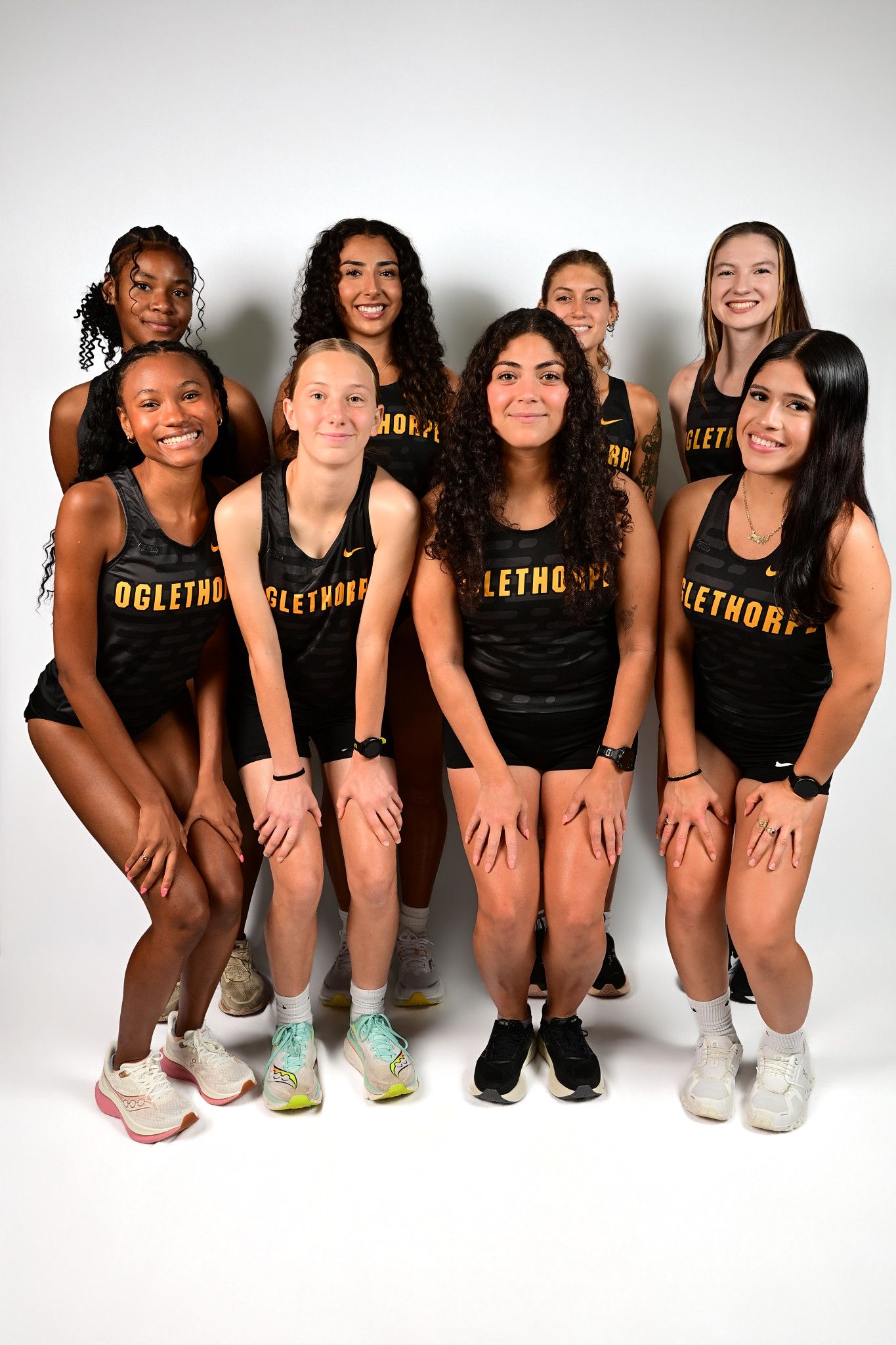 Oglethorp women's track and field team posing together in black and gold uniforms.